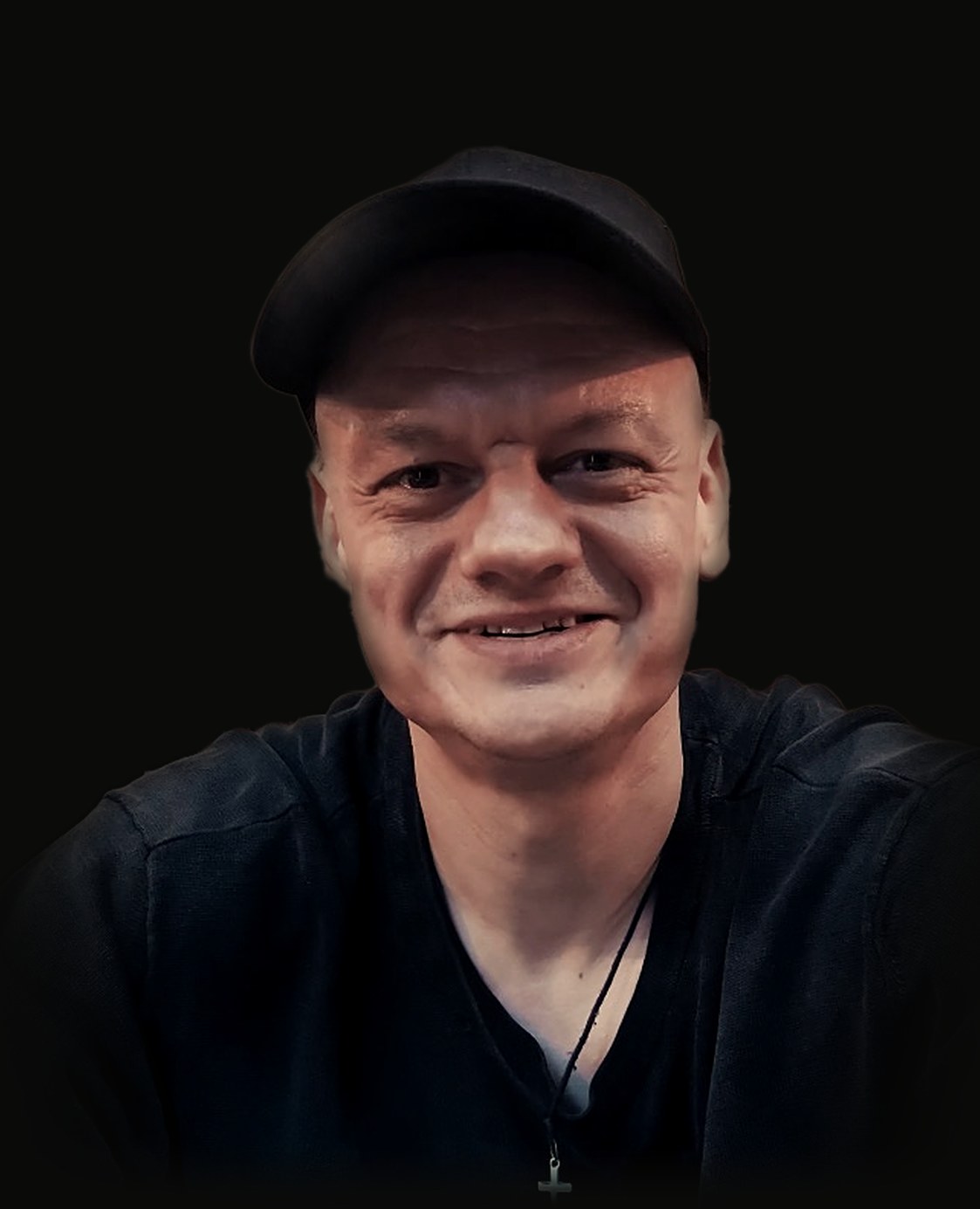 Gabriel Wilk smiling, in a dark cap and t-shirt, wearing a cross
